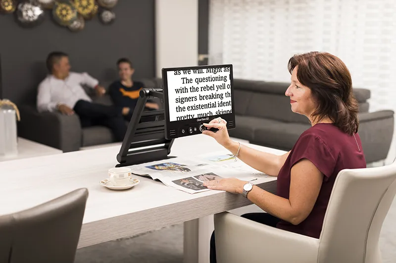 Person am Optelec Clearview Go liest Magazin